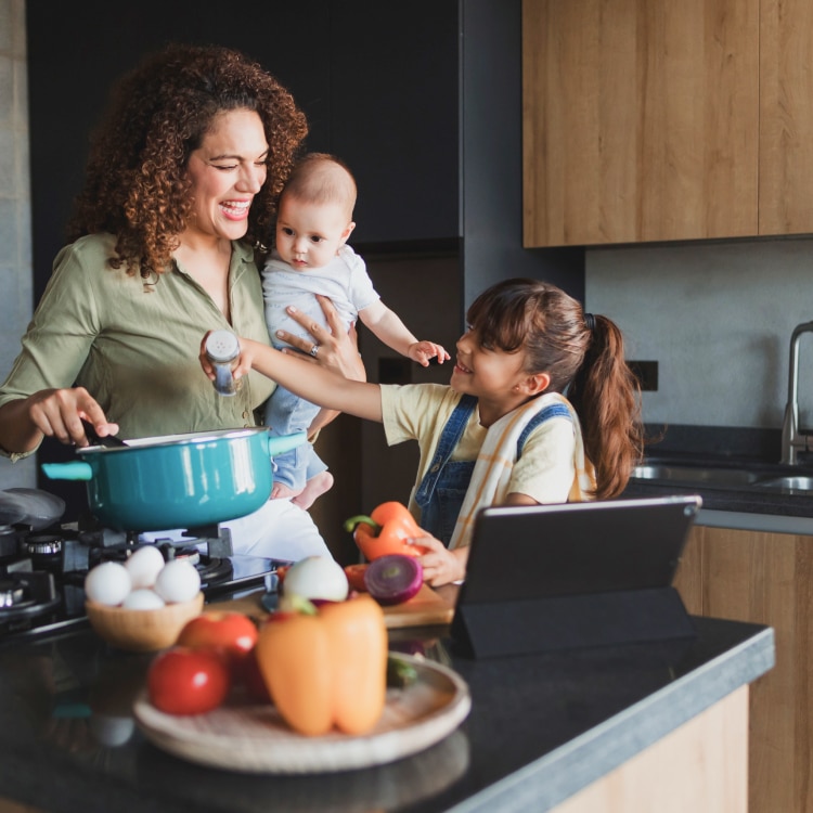 Mother and children cooking in kitchen with stone countertop.